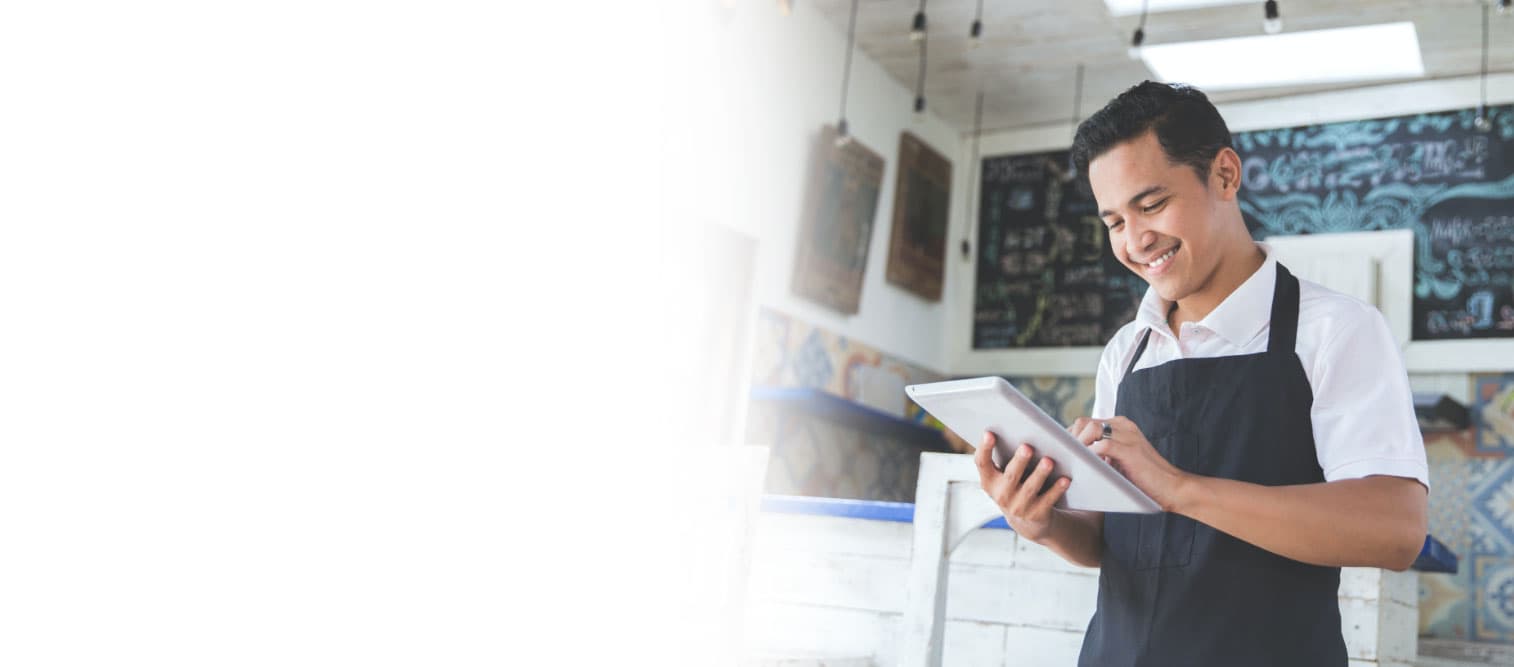 A shop owner smiling as he interacts with a tablet.