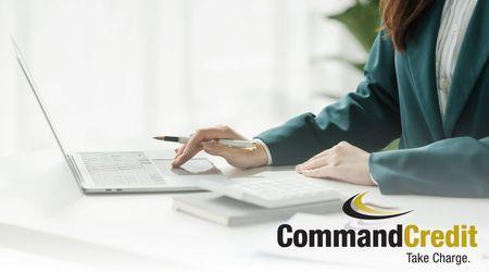 A business-woman sitting at a desk, using a laptop and a calculator.